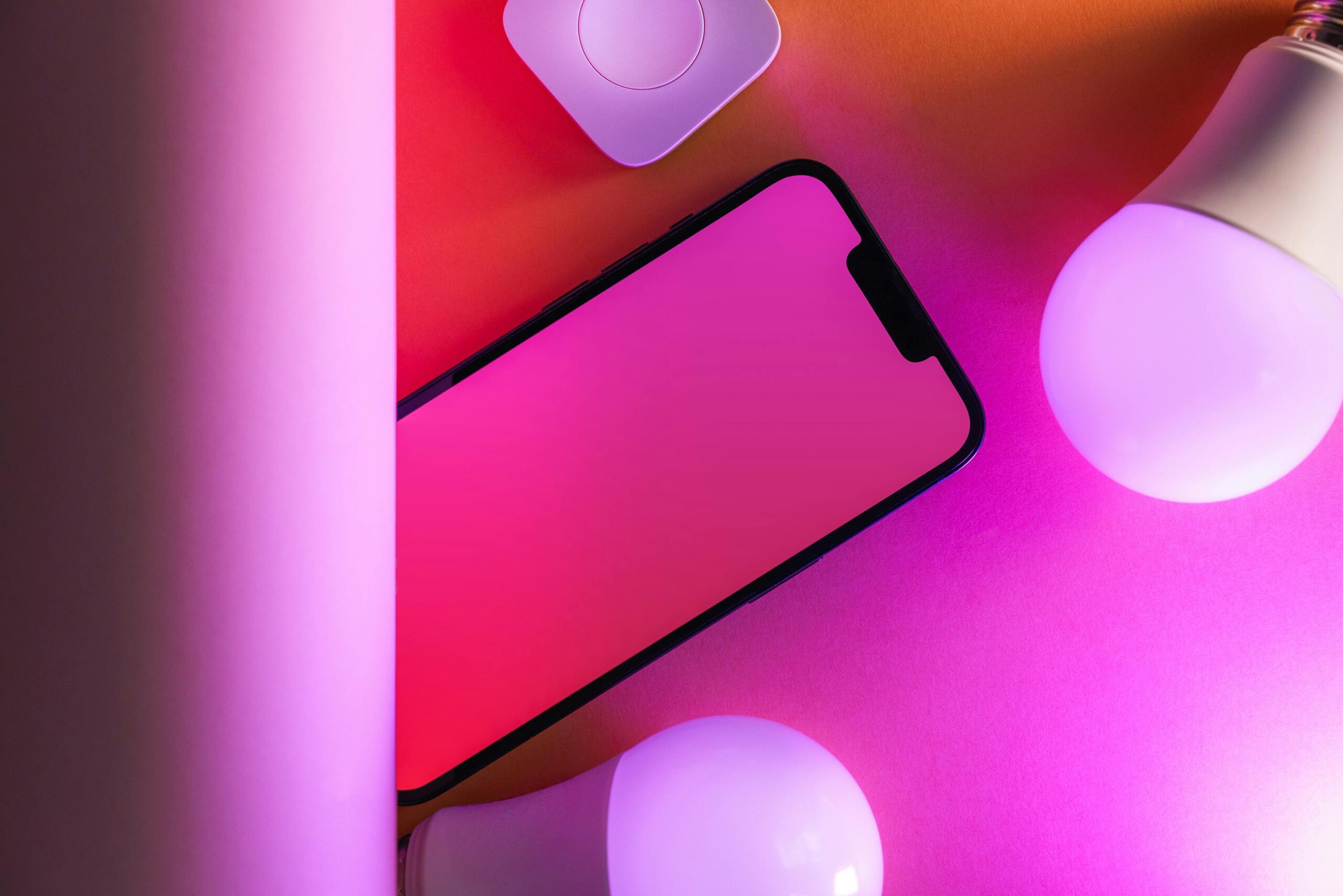 Colorful tech arrangement with smartphone and smart bulbs, perfect for modern design concepts.